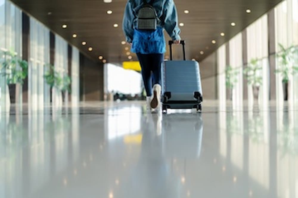 Viajante com mala andando com transporte de bagagem no terminal do aeroporto